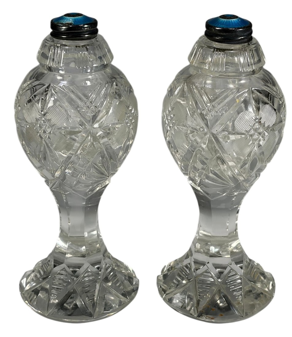 Pair Cut Crystal Sterling Salt & Pepper Shakers: Pair of cut crystal salt and pepper shakers with sterling silver and blue guilloche enamel lids. Features an intricate hobstar and geometric cut pattern with faceted pedestal bases. The silver mounts 