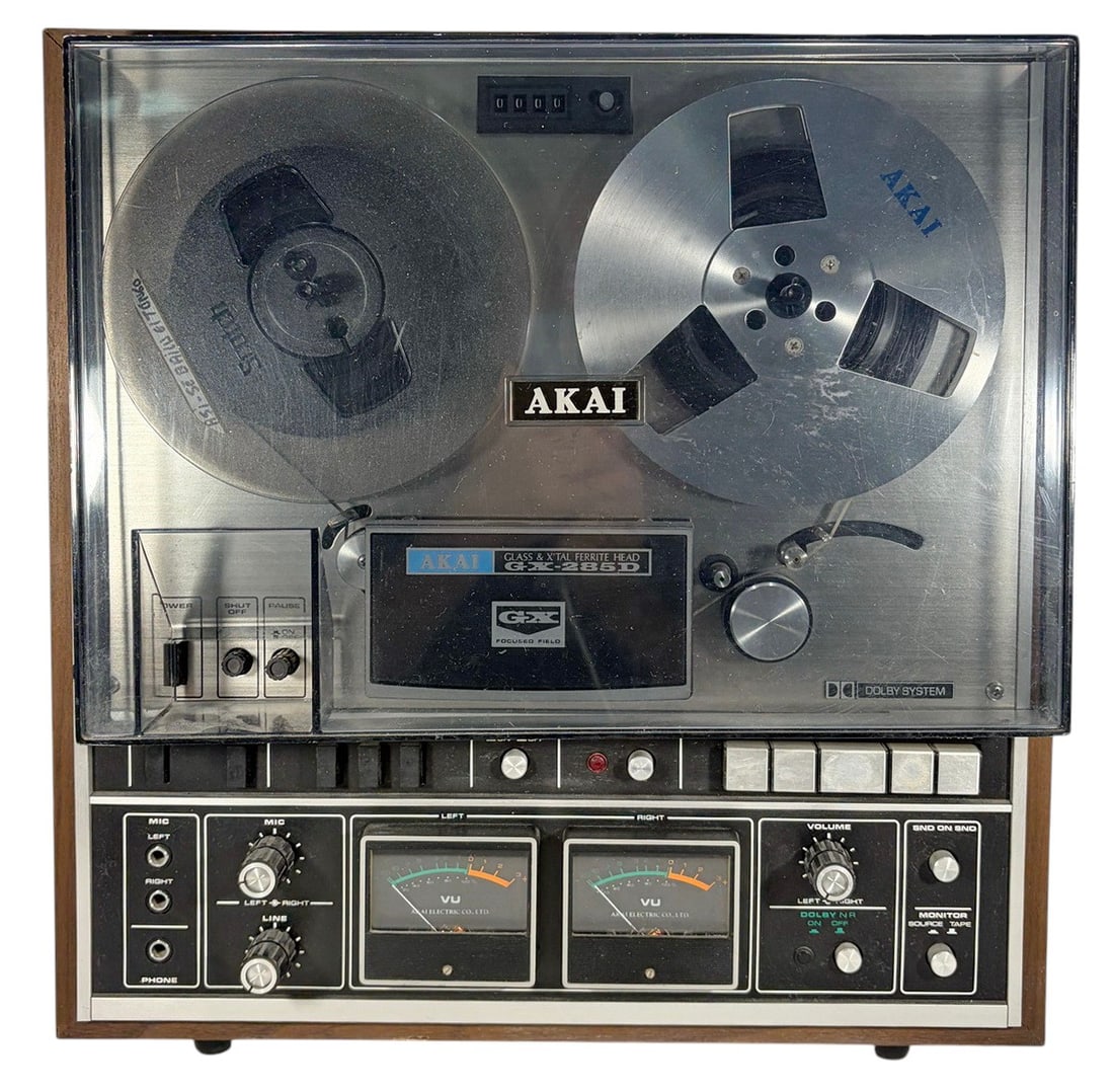Akai GX-285D Reel to Reel Tape Recorder Deck: Vintage Akai GX-285D reel-to-reel tape recorder with wood cabinet, clear dust cover, dual VU meters, and reel hubs. Features Akai's Glass & X'Tal Ferrite Head (GX) system. Includes one Akai metal take