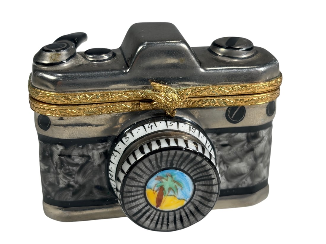 Artoria Limoges Camera Hinged Trinket Box France: French hand-painted Artoria Limoges porcelain hinged trinket box modeled as a vintage camera with gilt metal mounts. Features detailed camera controls and a lens decorated with a tropical beach scene.