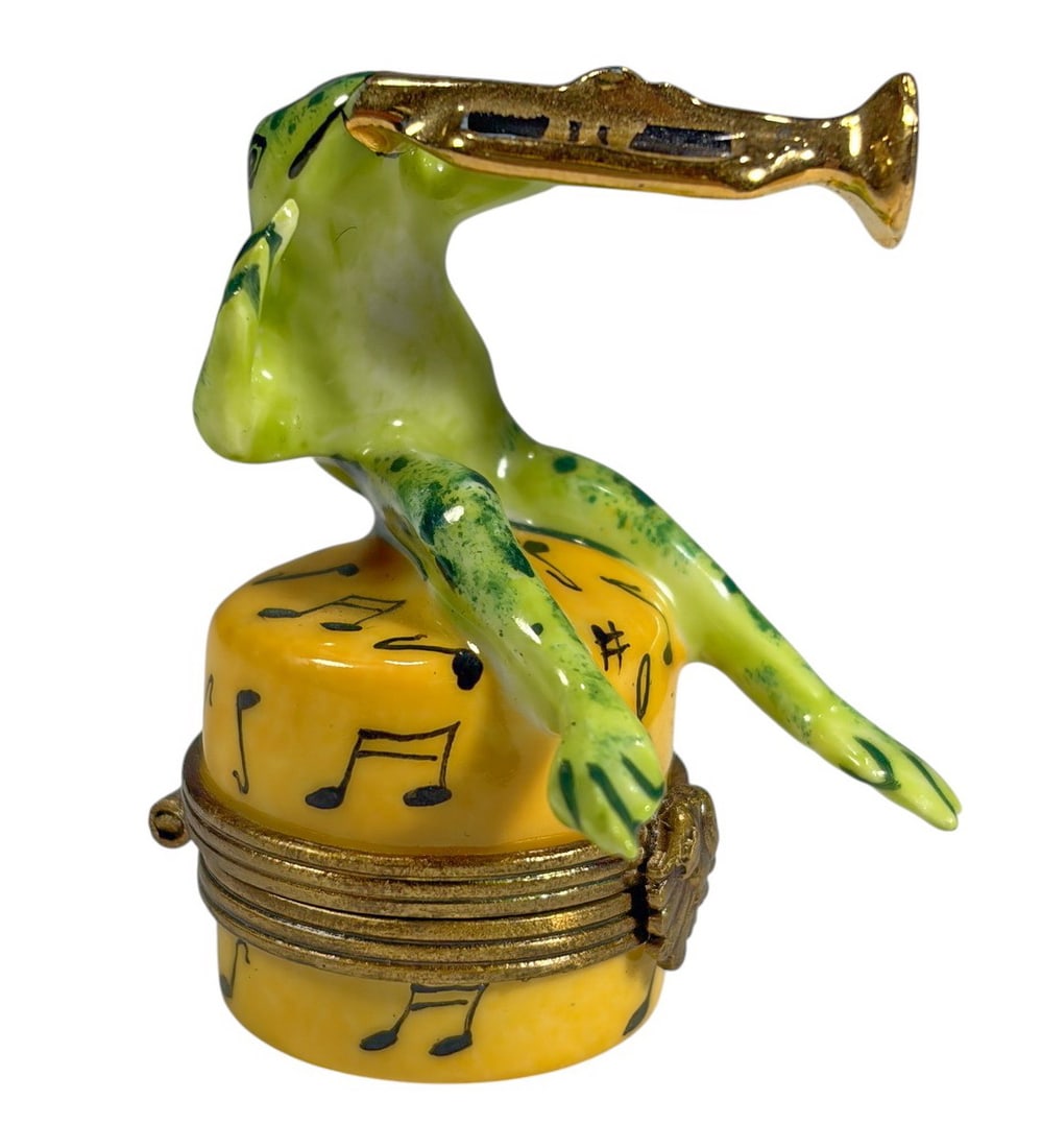Cardinet Frog Trumpet Limoges Trinket Box France: Hand-painted Cardinet Limoges France porcelain trinket box featuring a green frog playing a gold-tone trumpet while perched atop a yellow drum decorated with musical notes. Gilt-tone metal mounts. Mar