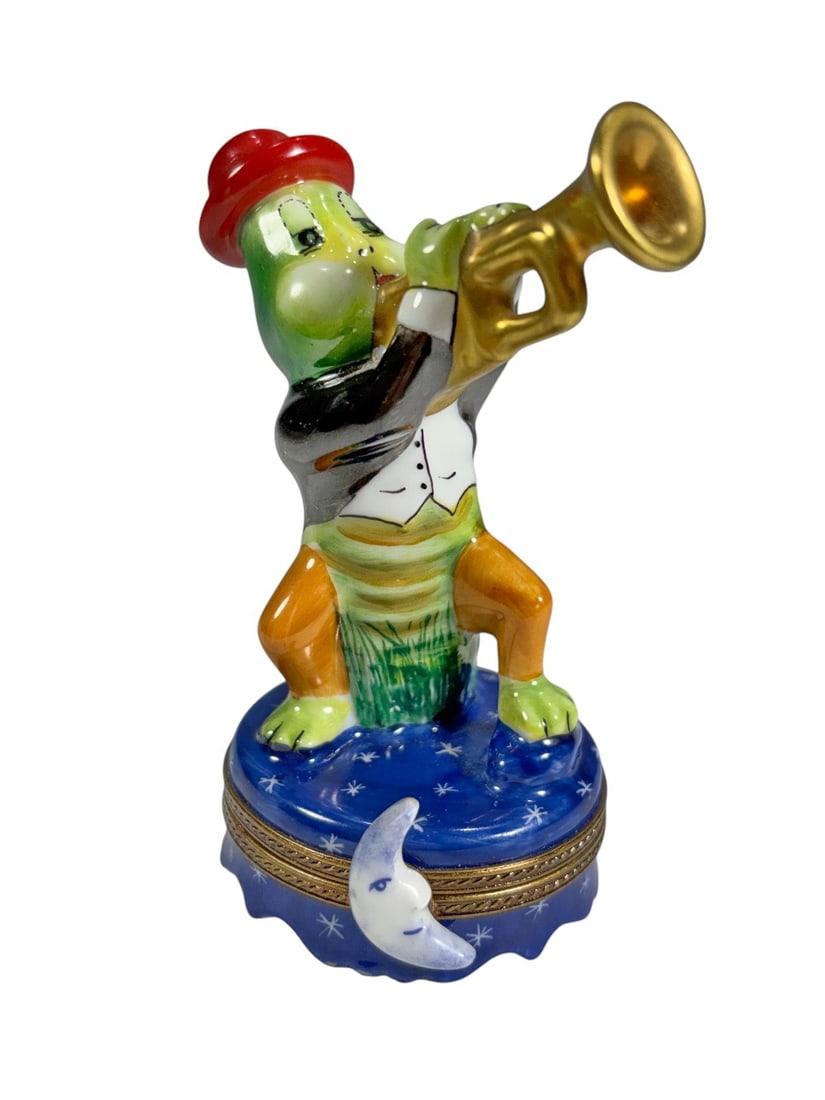 Limoges Peint Main Frog Trumpeter Trinket Box Fran: French Limoges porcelain hinged trinket box modeled as a frog playing a trumpet, hand painted with vibrant colors and gilt metal mounts. The interior features a gold shooting star motif, and the base 