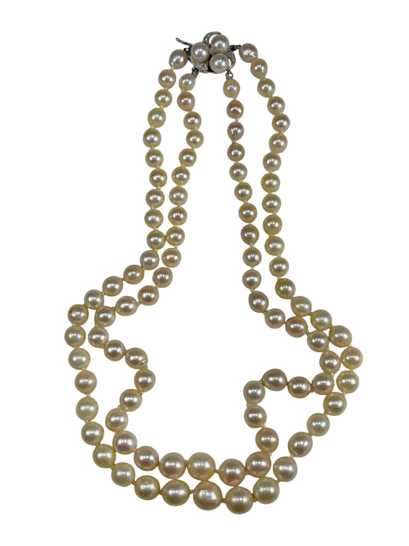 14K White Gold Pearl Diamond Necklace: Double strand pearl necklace composed of cream white pearls with individually knotted construction. Features a decorative 14K white gold clasp set with three larger pearls and accented with a small br