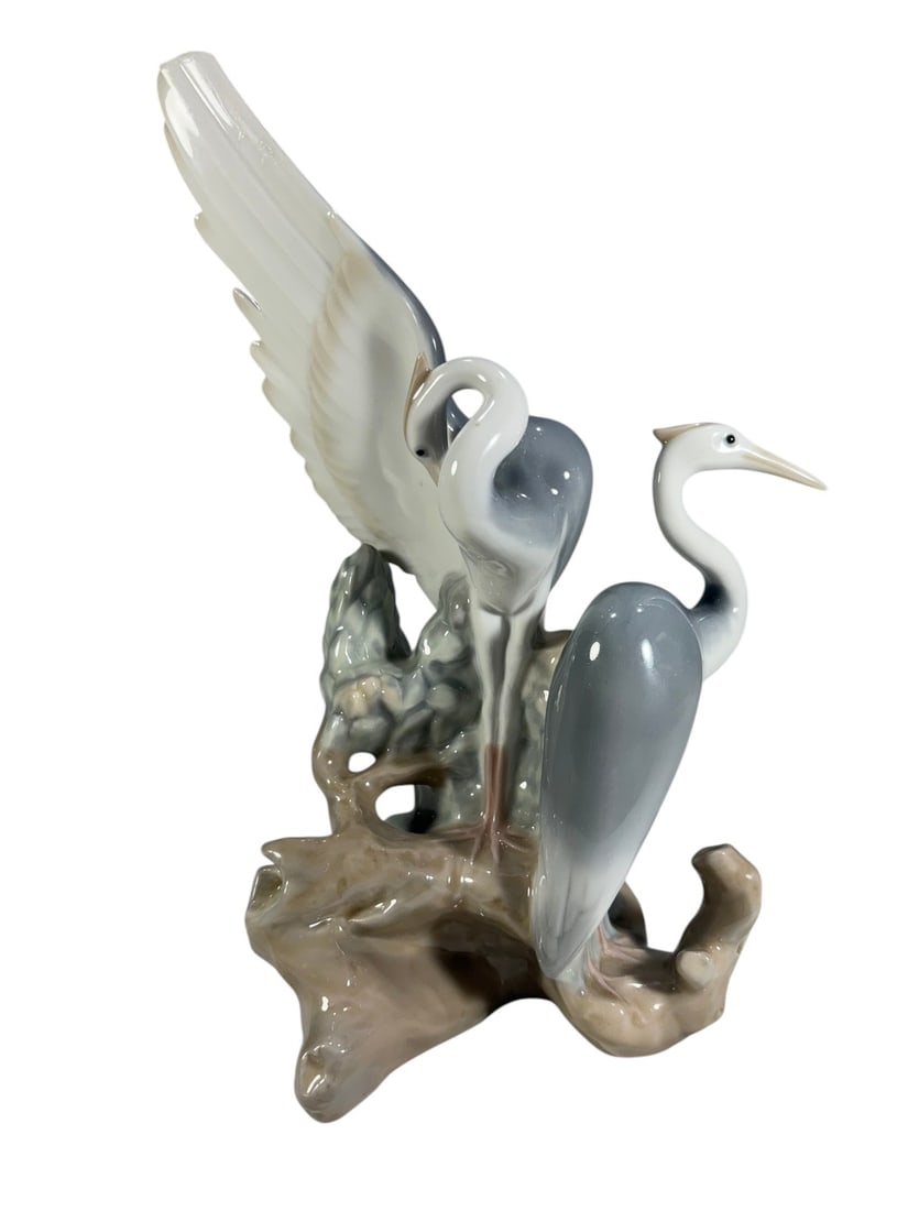 Nao Lladro Spain Porcelain Pair of Herons Figurine: Nao by Lladro Spanish porcelain figural group depicting two elegant herons perched together on a naturalistic tree form. Finished in a glossy pale gray, blue, white, and beige palette, with one bird d