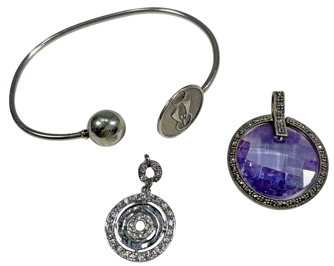 Sterling Silver Pendants & Bracelet Jewelry 3pcs: Group of three sterling silver jewelry items comprising two pendants and one open cuff bracelet. One large circular pendant is set with a faceted violet colored glass stone surrounded by marcasite sty