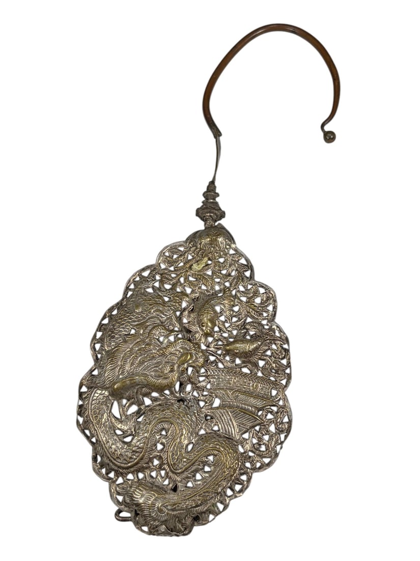 Chinese Silver Dragon Openwork Hanging Ornament: Chinese silver openwork ornament richly decorated with a coiled dragon among pierced floral and foliate motifs. The elongated scalloped form is fitted with a curved suspension hook and rear support ba