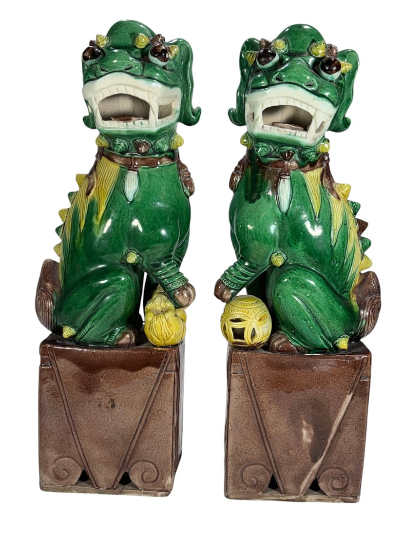 Pair of Chinese Green Glazed Ceramic Foo Dogs: Pair of Chinese glazed ceramic guardian lions, or Foo Dogs, modeled seated on tall rectangular brown-glazed plinths. Each figure is finished primarily in a rich green glaze with contrasting yellow,