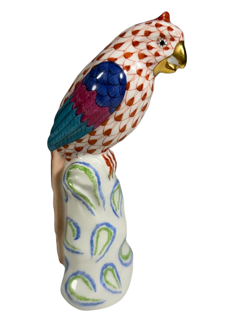 Herend Hungary Porcelain Fishnet Parrot Figurine: Hand-painted Herend Hungary porcelain parrot figurine, model No. 5004, perched on a stylized decorative base. The bird is decorated in Herends characteristic red fishnet pattern with vivid blue,