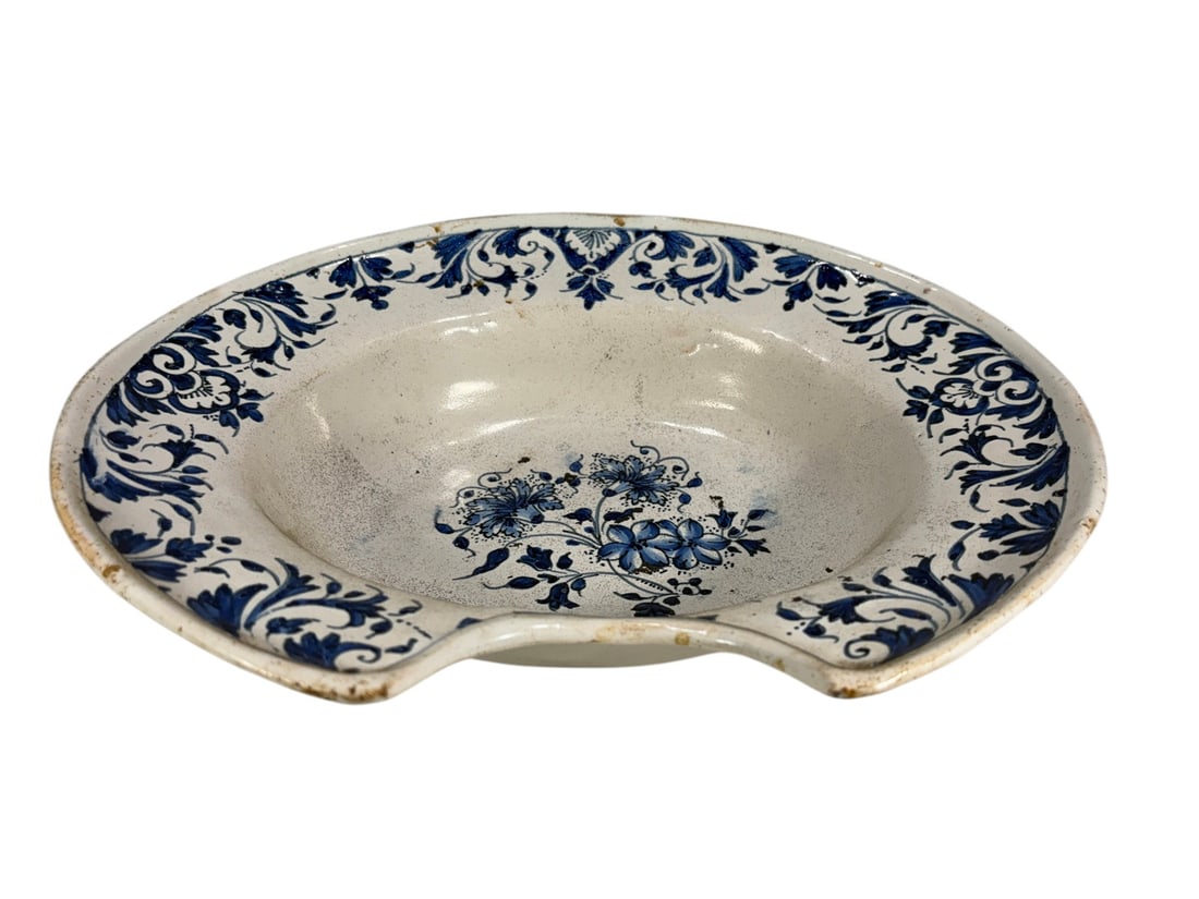 17th C. Blue & White Delftware Shaving Basin: A blue and white Delftware shaving basin dating to circa 16601680, formed with a semicircular cutout along the rim to fit around the neck during shaving. The basin is decorated in cobalt blue with scr