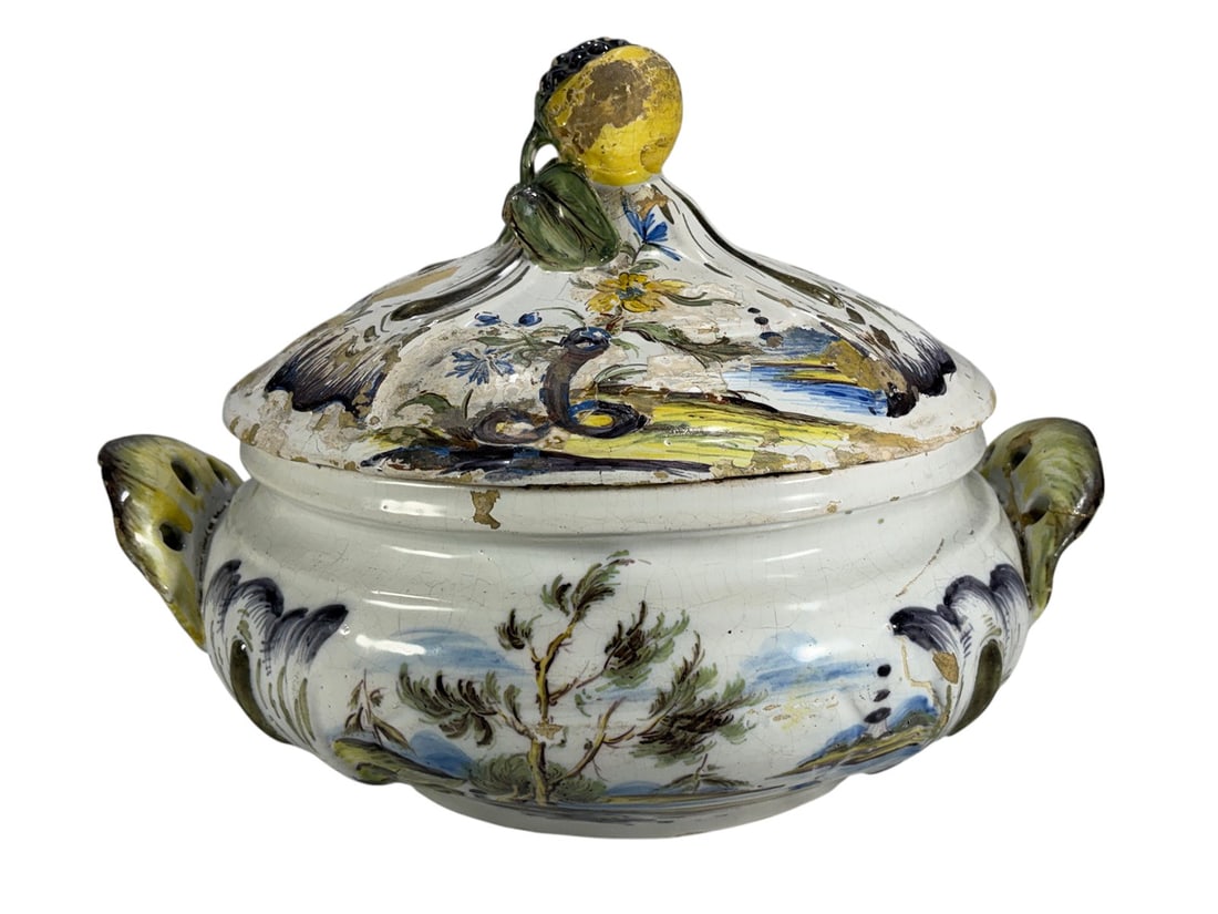 18th C. Italian/ French Maiolica Landscape Tureen: Large Italian maiolica covered tureen, probably 18th century, of bulbous oval form with pierced shell-form side handles and a domed cover surmounted by a modeled fruit-and-leaf finial. The tin-glazed 