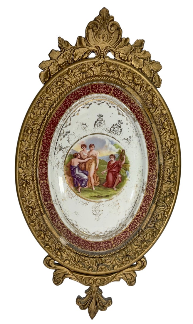 Vintage Classical Porcelain Plaque in Ornate Frame: Decorative oval porcelain plaque featuring a hand-painted classical scene with four female figures in a pastoral landscape. The porcelain is embellished with gilt ornamental motifs and a deep burgundy