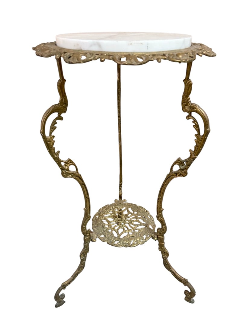 Ornate Brass Marble Top Plant Pedestal Stand: Vintage decorative stand featuring an ornate cast-metal frame with a gold-tone finish and an inset round white marble top with subtle natural veining. The frame is designed with elaborate scrollwork, 
