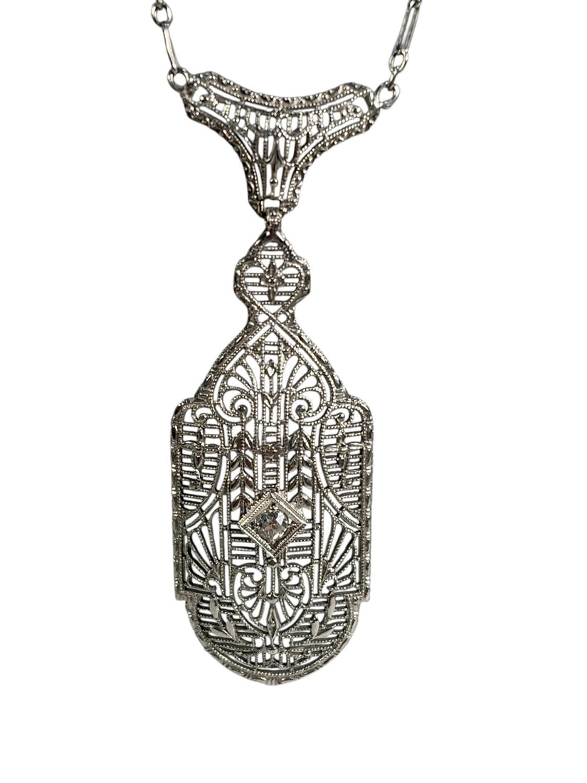 Art Deco Platinum Filigree Pendant, 14K Gold Chain: Elegant Art Deco platinum filigree pendant suspended from a 14K gold chain. The finely pierced pendant features intricate geometric and scrollwork decoration accented by a small clear faceted stone at