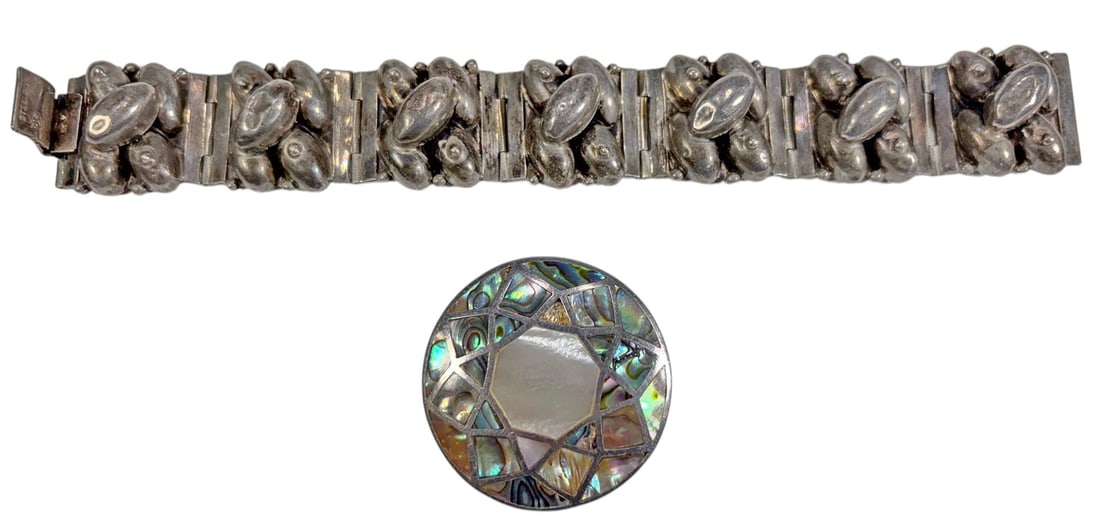Mexican Sterling Silver Bracelet & Compact 2pc LOT: Two-piece lot comprising a Mexican sterling silver articulated bracelet and a round inlaid compact. The bracelet is composed of linked panels decorated with sculptural applied motifs and is marked STE