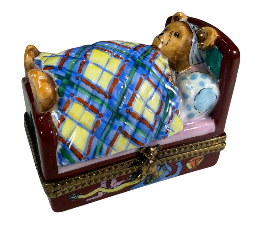 Limoges France Teddy Bear Bed Trinket Box: Whimsical hand-painted Limoges France porcelain trinket box modeled as a teddy bear tucked into bed beneath a colorful plaid blanket. The raised figural design includes a red-brown bed frame, patterne
