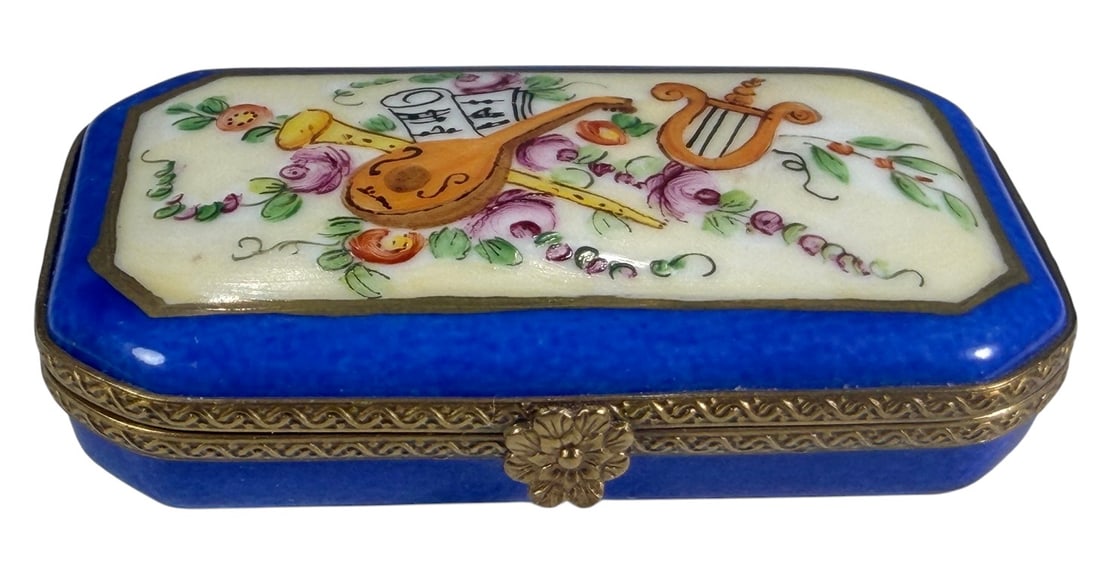 Limoges France Musical Instruments Trinket Box: Hand-painted Limoges France porcelain trinket box of rectangular form with beveled corners, decorated with musical instruments including a lute, horn, and lyre, surrounded by floral motifs and sheet m