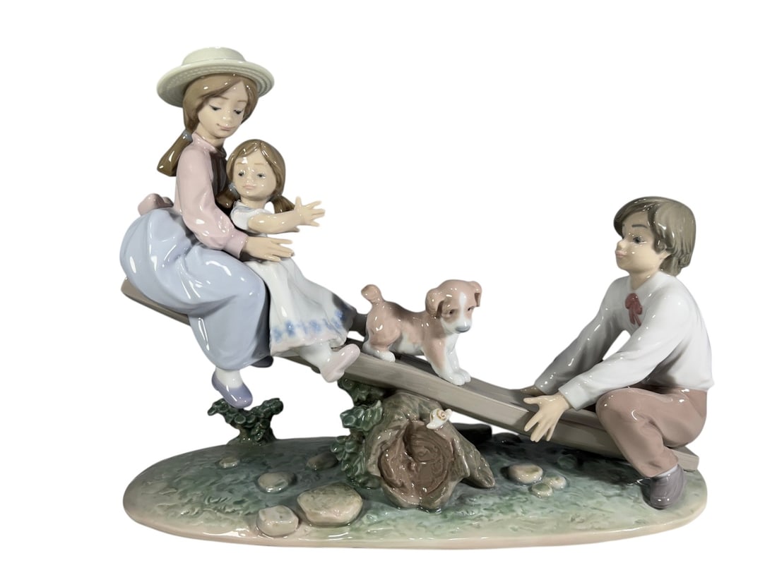 Lladro Spain 6169 Seesaw Friends Porcelain Fig: Lladro glazed porcelain figurine titled 'Seesaw Friends,' model No. 6169, depicting three children playing on a seesaw with two puppies. Finely modeled in soft pastel tones and marked Lladro, Hand Mad