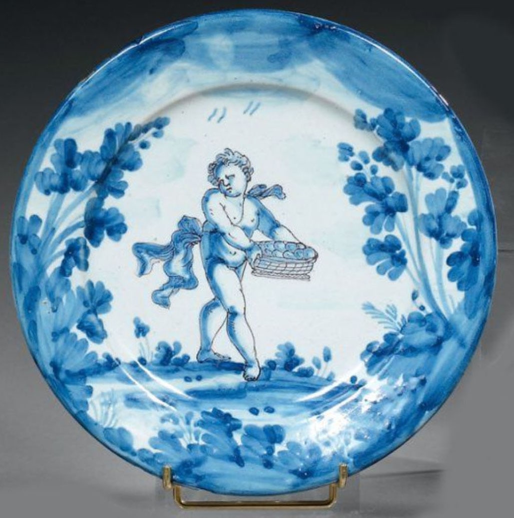Ceramic Dish: Round plate decorated in blue monochrome with a putto carrying a basket of fruit in a landscape.D: 24 cm