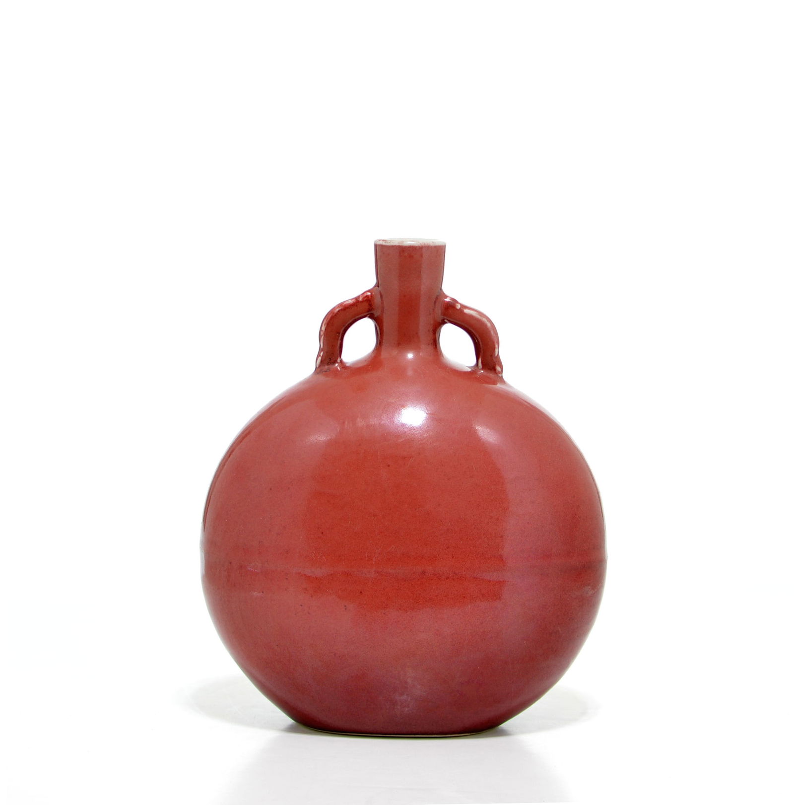 Rare Chinese Copper-Red Moonflask Vase: Inspired by 15th-century Middle Eastern metalware, this moon flask features a distinctive compressed globular body set with a narrow neck and twin arched handles. The vessel is enveloped in a rich