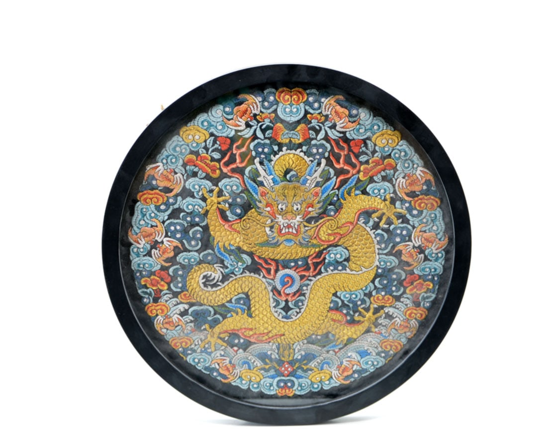 A Chinese Embroidered Silk 'Front-Facing Dragon' Roundel: The circular panel is exquisitely worked in couched gold and vibrant polychrome silk threads on a dark ground. It features a powerful front-facing five-clawed dragon (zhenglong), its undulating,