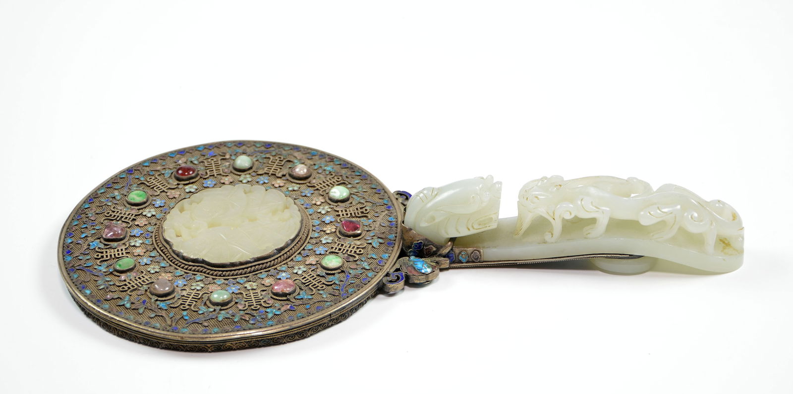 Chinese Jade-Inlay Mirror: The circular mirror plate is set within a finely worked silver-gilt filigree mount, the reverse centered with a large, pierced white jade circular plaque carved with boys figure motifs. The