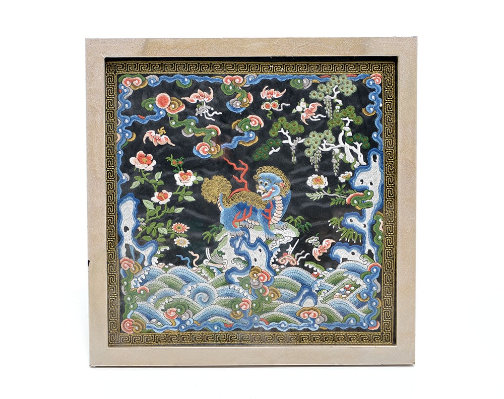 Framed Chinese Silk Embroidery Badge: This square silk rank badge, or buzi, is meticulously embroidered in colorful silk and couched gold threads on a black ground. The central figure is a lion, depicted standing on a rocky outcrop