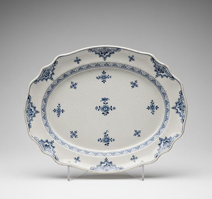 Blue and White Dish: Oval ceramic dish featuring blue floral and geometric patterns on a white glazed surface. The scalloped rim is decorated with repeating motifs, while the center contains several small floral sprays.