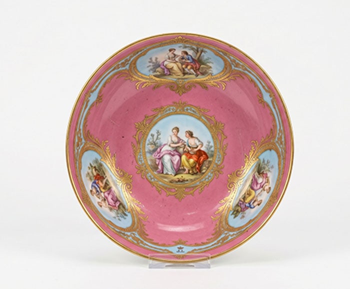 Ceramic Dish: Pink and blue ceramic dish features a central painted scene of two figures and four smaller scenes along the inner rim. Brass scrollwork accents the divisions between the colored sections. D: 17 CM