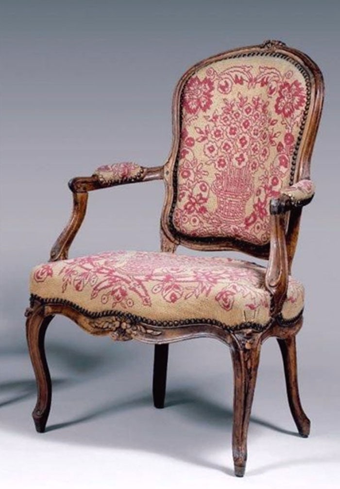 Walnut Chair: Armchair with a carved wooden frame and red floral pattern fabric on the seat and backrest. Small brass tacks line the edges of the upholstery. The frame includes curved legs and padded armrests. H: