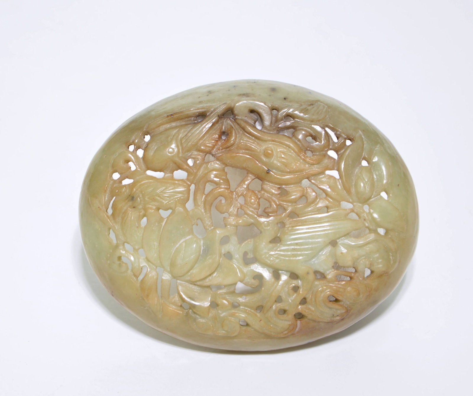 Chinese Openwork Jade Plaque: Jade plaque of oval, domed form, masterfully carved in openwork to depict a crane amidst a lush arrangement of scrolling lotus blossoms and entwined foliage. The stone exhibits a subtle celadon tone, 