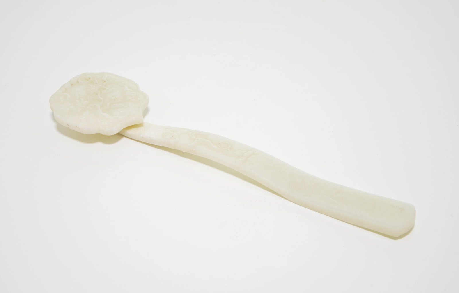 Chinese Carved Jade Ruyi Scepter: Ruyi scepter meticulously fashioned from a stone of pale celadon hue, possessing a soft, unctuous polish and gentle translucency. The lingzhi-shaped head is elegantly carved in low relief with traditi