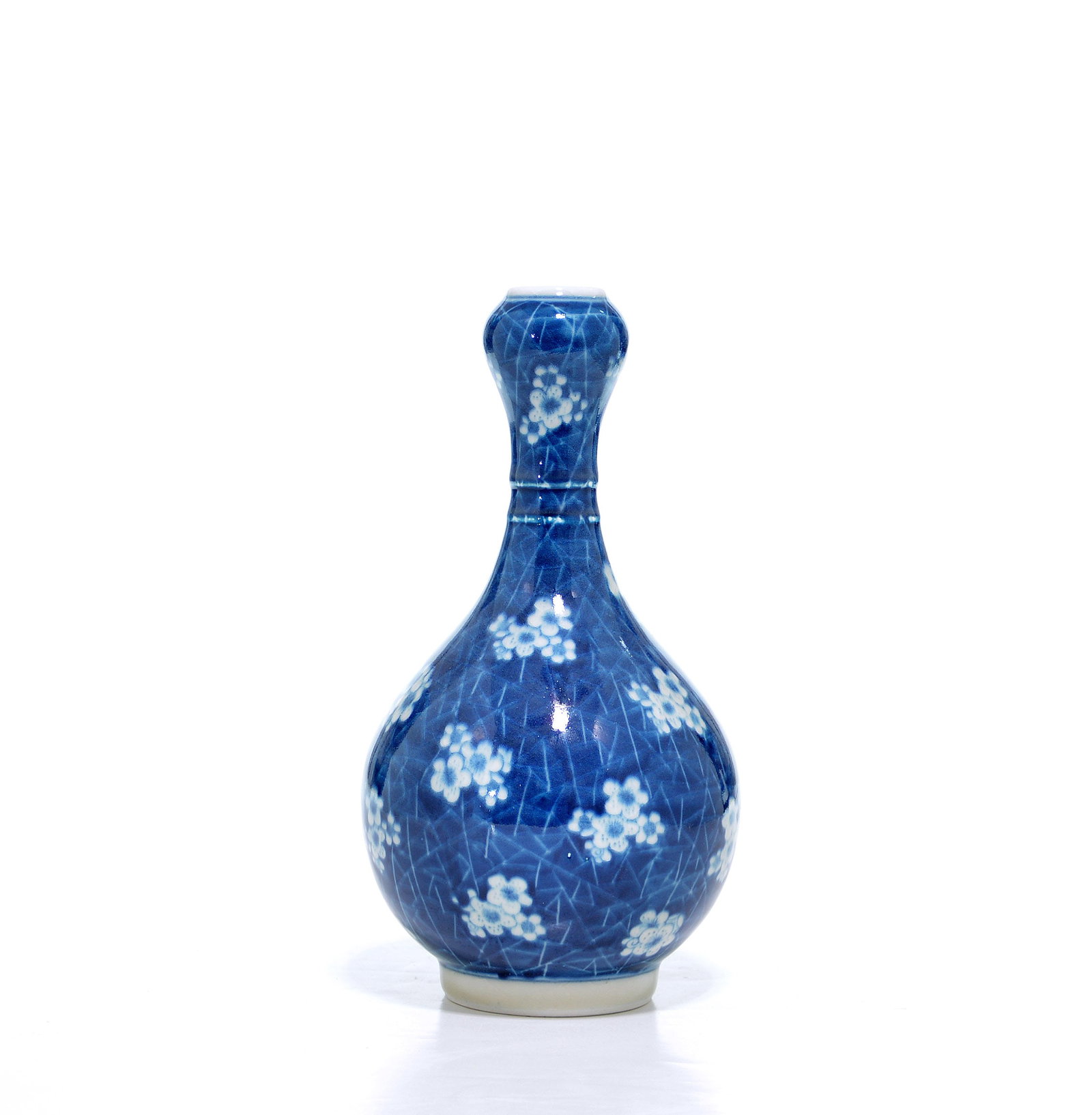 Chinese Blue And White 'Prunus' Vase: Garlic-head vase exquisitely rendered with a dense pattern of white prunus blossoms reserved against a deep cobalt 'cracked ice' ground. The bulbous neck and swelling body exhibit a harmonious