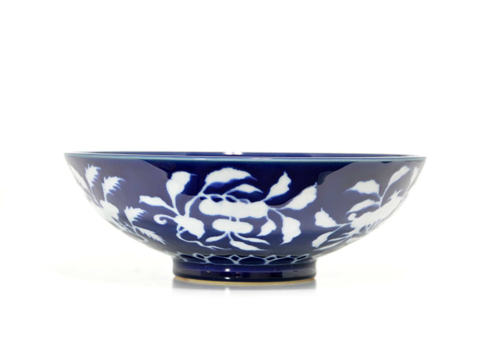 Fine Chinese Reverse-Decorated 'Fruit' Bowl: Bowl of elegant proportions, the exterior meticulously decorated with reserved white flowering sprays of pomegranate and peach against a rich cobalt blue ground. The lower body is further accented by