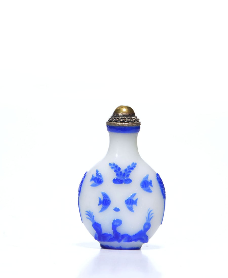 Chinese Suchow-School Glass Snuff Bottle: Snuff bottle of flattened globular form is composed of opaque white glass, expertly overlaid with sapphire blue glass to create a dynamic relief. The decorative scheme features a lively array of carp