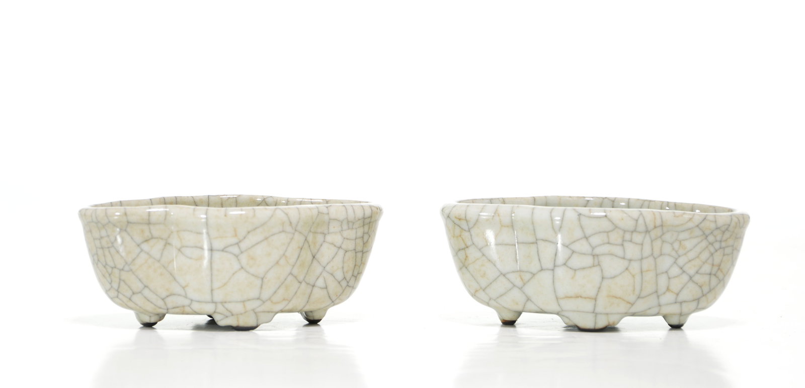 Pair of Chinese 'Guan-Type' Lotus Bowls: Bowls of elegant cloud-lobed form, each skillfully potted with an undulating rim and supported on three small tapered feet. The pale greyish-celadon glaze is densely suffused with a network of bold