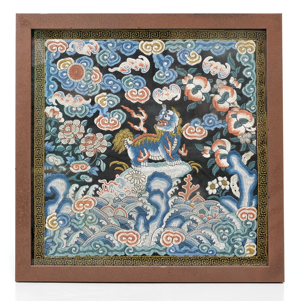 Chinese Embroidered Rank Badge: Embroidered silk rank badge centered with a lion positioned atop a rocky plinth amidst swirling waves and auspicious ruyi-shaped clouds. The mythical creature is surrounded by stylized bats and floral