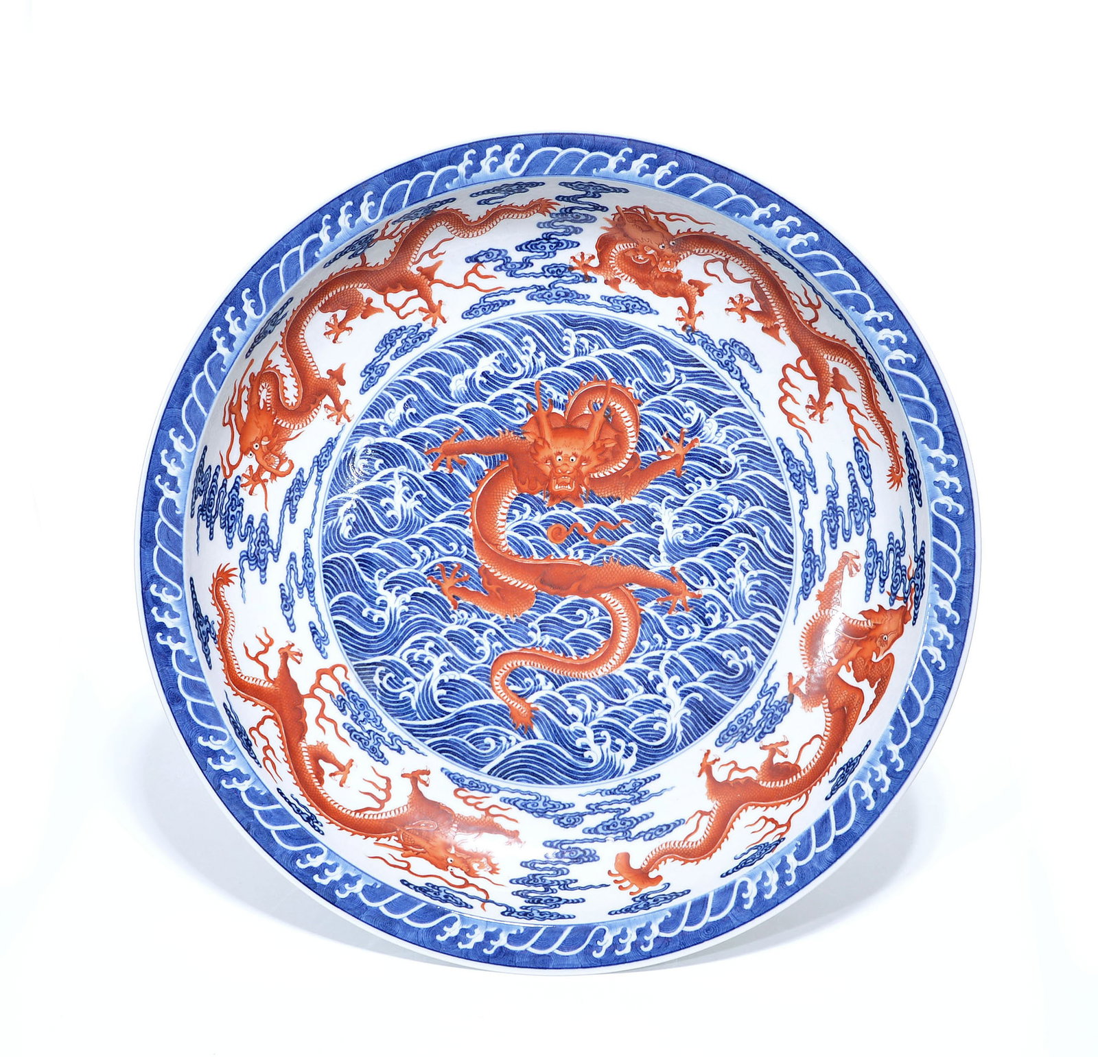 Extremely Fine and Large Chinese Iron-Red Dragon Dish: Dish of grand proportions, expertly decorated with a central iron-red dragon leaping from underglaze blue turbulent waves. The cavetto and exterior are masterfully painted with multiple writhing drago