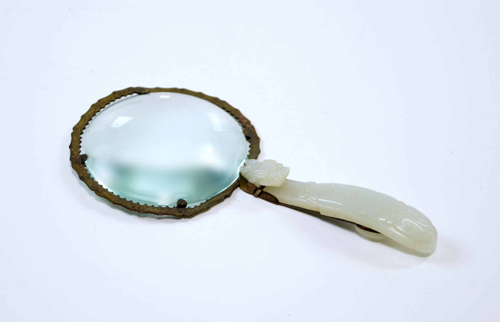 Chinese Jade Magnifying Glass: Magnifying glass featuring a translucent pale green jade handle intricately carved as a dragon belt hook. Qing dynasty. Jade Length: 9 CM, Full Length: 16.2