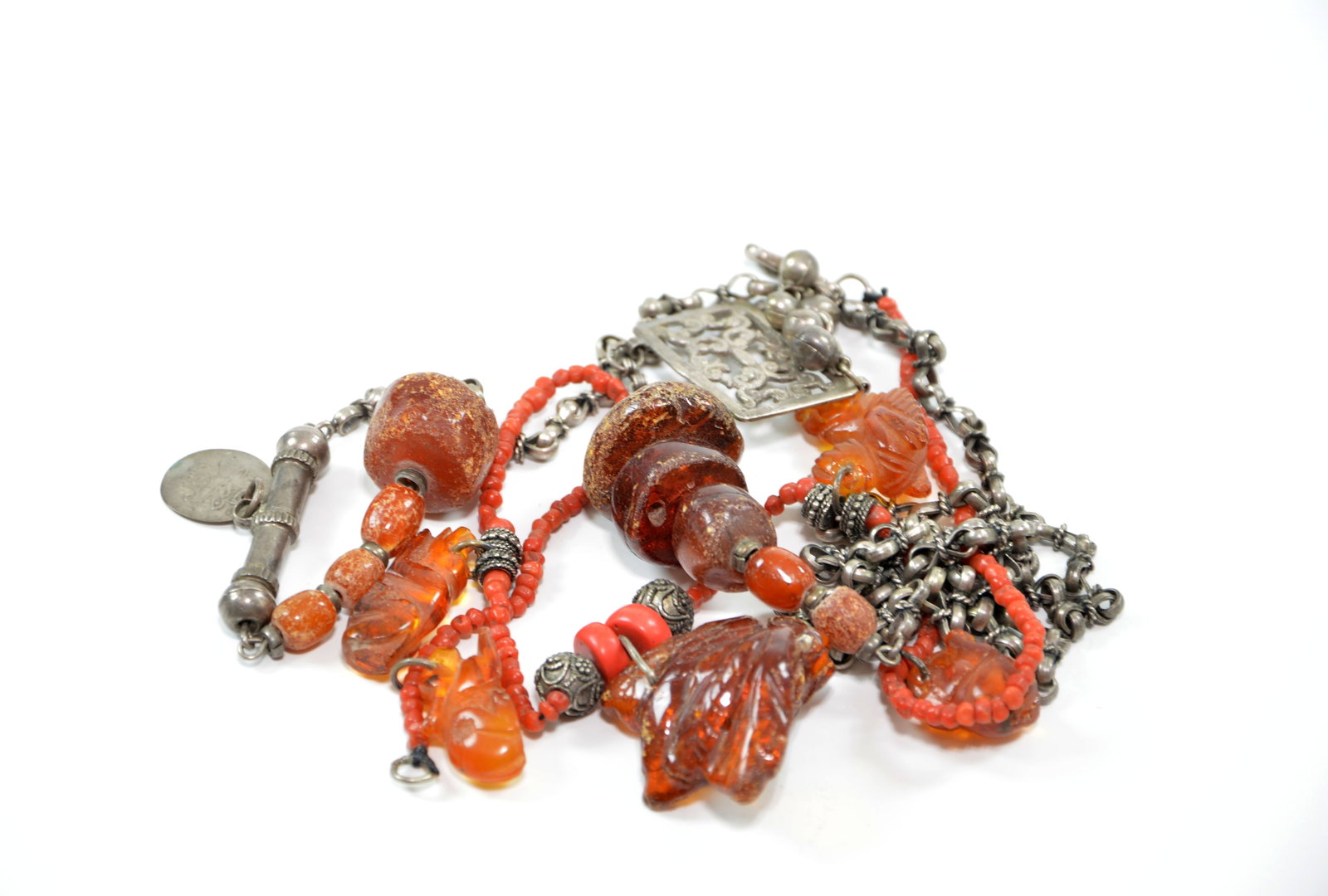 Chinese Amber Jewelry: Necklace assembly featuring a sophisticated arrangement of carved amber pendants and decorative white metal elements. 19th century. Largest Amber Length: 4 cm