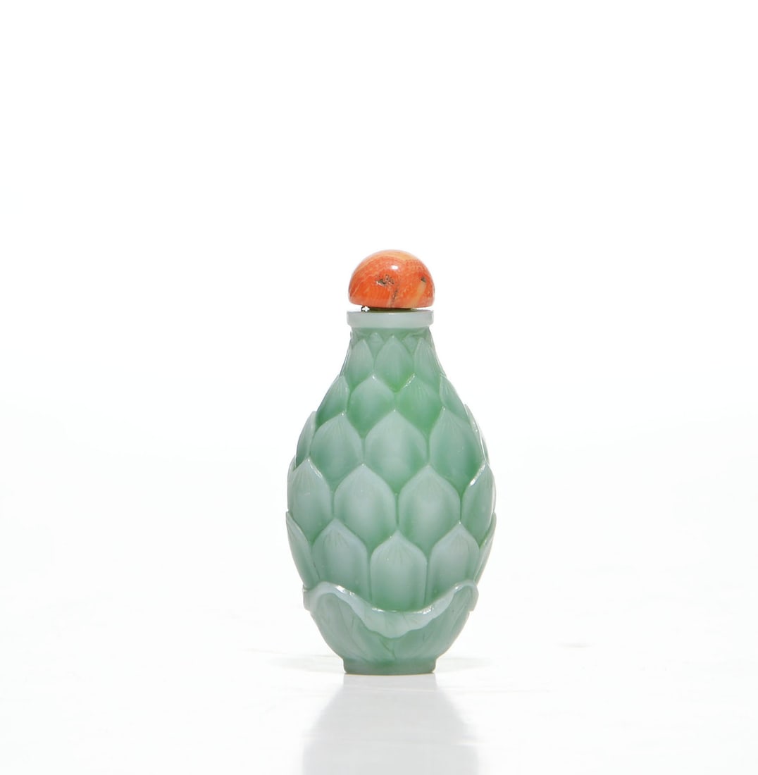 Chinese Glass 'Lotus' Snuff Bottle: The ovoid glass body is modelled in tiers of overlapping lotus petals beneath a short cylindrical neck, and covered in a pale celadon glaze. It is fitted with a domed, mottled orange stopper with