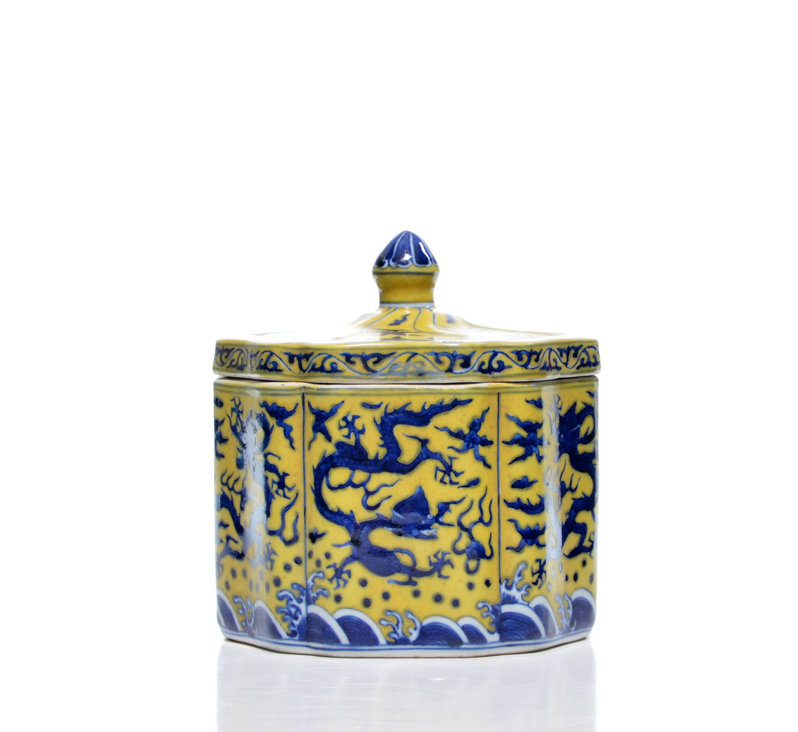 Fine Chinese Yellow-Enamel Dragon Covered Jar: Of faceted cylindrical form, the jar is decorated in underglaze blue against a yellow ground with striding dragons amid cloud scrolls above a band of crashing waves. The domed cover is finished with