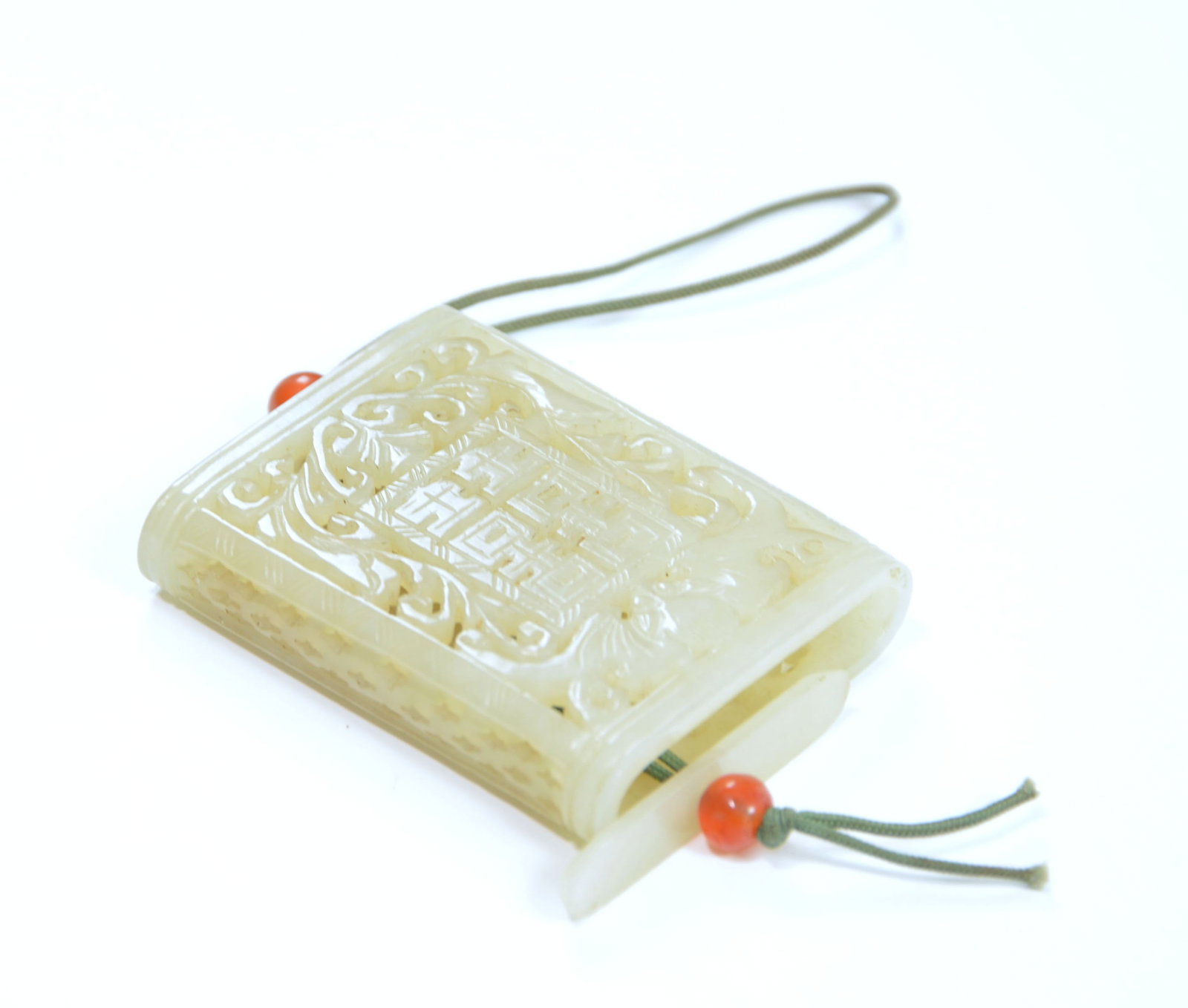 Chinese Carved Jade 'Double-Happiness' Pendant: The translucent pale celadon jade pendant is carved in the form of a rolled scroll, with a rectangular central panel enclosing a stylised character amid foliate scrollwork and archaistic motifs. The