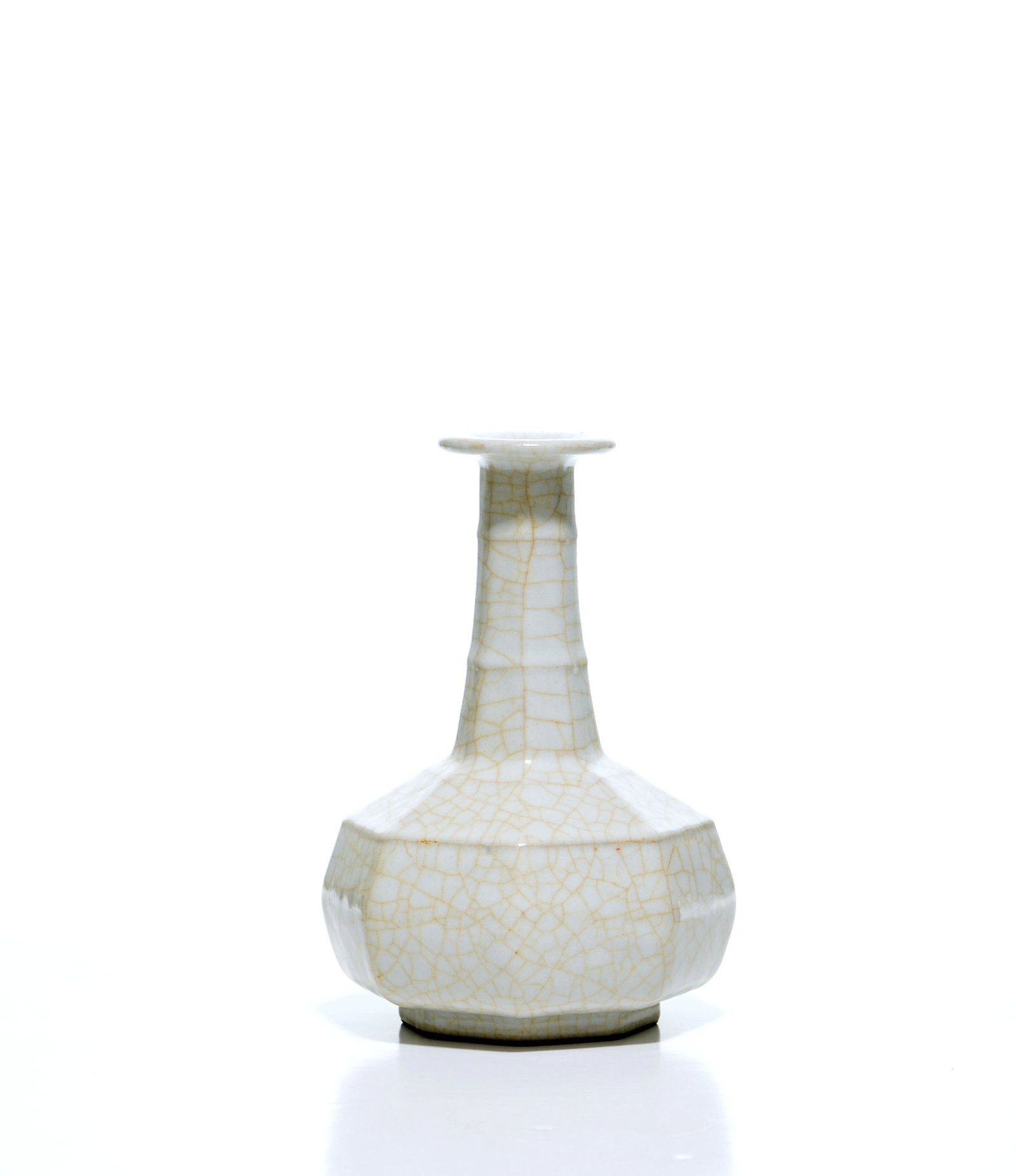 Chinese 'Guan-Type' Octagonal Vase: The vase is modelled with a compressed, faceted octagonal body rising through a tapered neck to a flared rim, supported on a conforming octagonal foot. It is covered overall in a creamy glaze