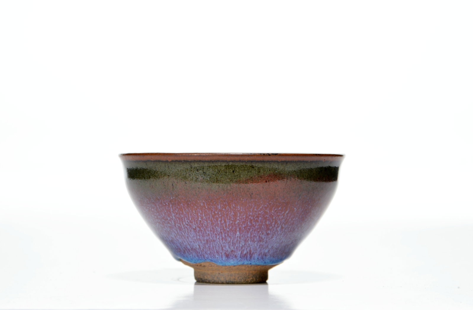 Chinese Mottled-Glazed Stoneware Bowl: The bowl is potted with a gently flared rim, rounded sides tapering to a short, slightly splayed foot. The exterior is covered in a mottled russet glaze suffused with pale blue streaking, below a dark