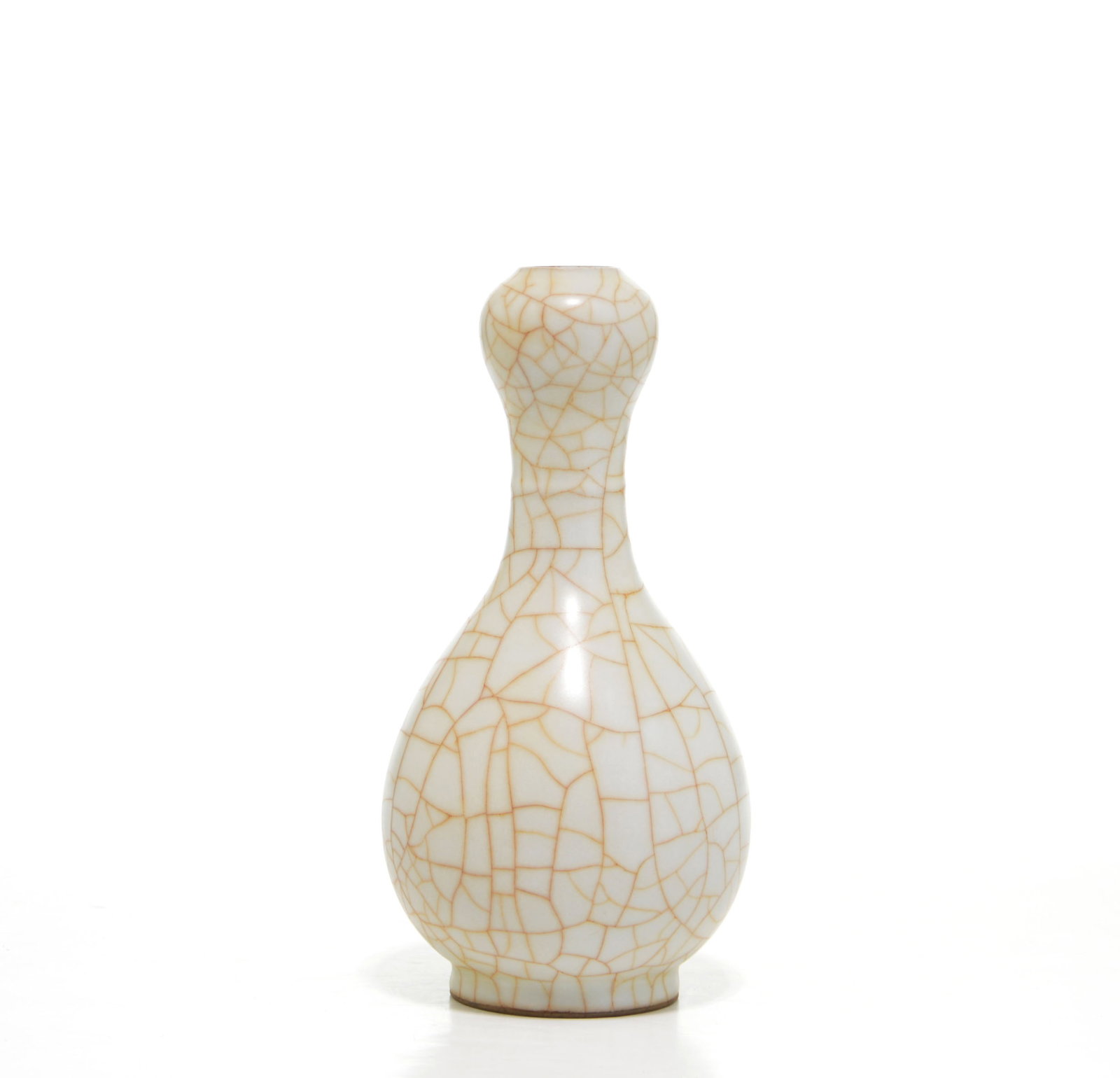 Chinese Crackle-Glazed Garlic-Head Vase: The pear-shaped porcelain vase rises from a slightly tapered foot to a slender neck and garlic-head mouth. It is covered overall in a creamy glaze suffused with an irregular network of golden-brown cr