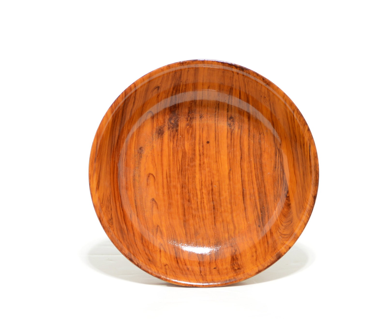 Chinese Faux-Bois-Glazed Bowl: The rounded porcelain bowl has a flared rim and a short, slightly splayed foot, and is covered inside and out in a warm amber-brown faux-bois glaze simulating figured wood grain. The recessed base