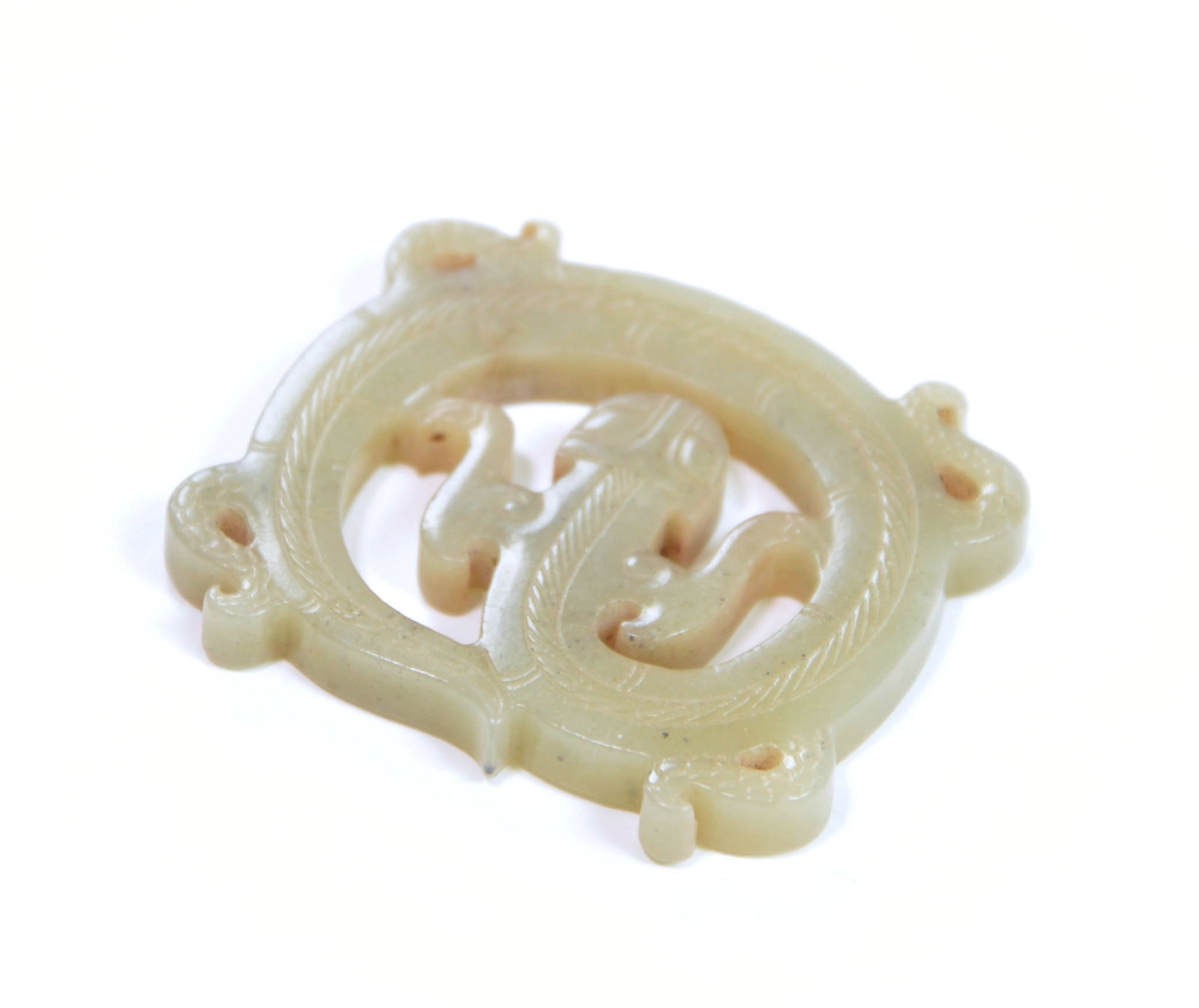 Chinese Jade Openwork Dragon Pendant: The pale celadon jade roundel is carved in openwork with a pair of intertwined stylised animal motifs within a circular band of incised linear decoration. Four projecting lobes punctuate the rim. The