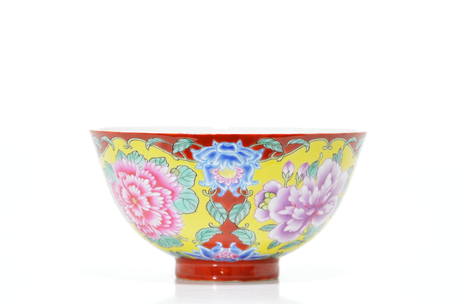 Chinese Falangcai-Style Floral Bowl: The rounded bowl is decorated in famille-rose enamels on a yellow ground with large peony blooms, leafy scrolls and stylised blue lotus motifs, reserved against iron-red diapered panels. It is raised