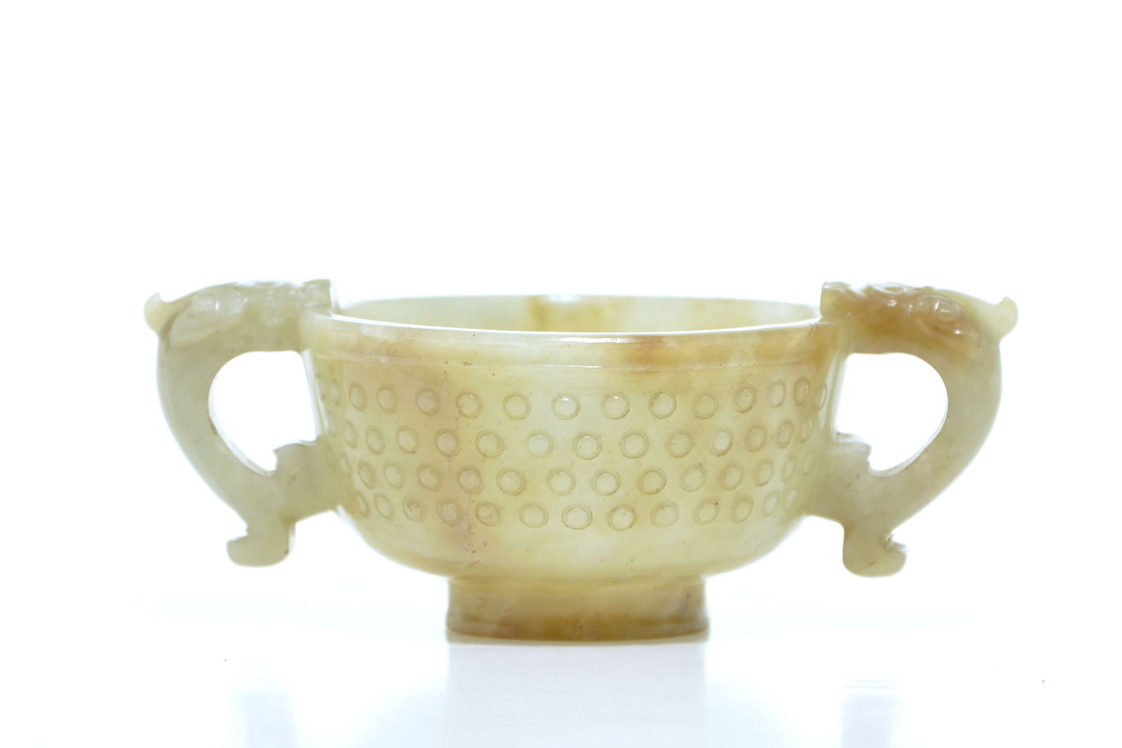Chinese Jade Cup: The pale yellowish-green, semi-translucent jade bowl is of compressed circular form, supported on a short, slightly flared foot. It is carved around the exterior with concentric rows of raised bosses 