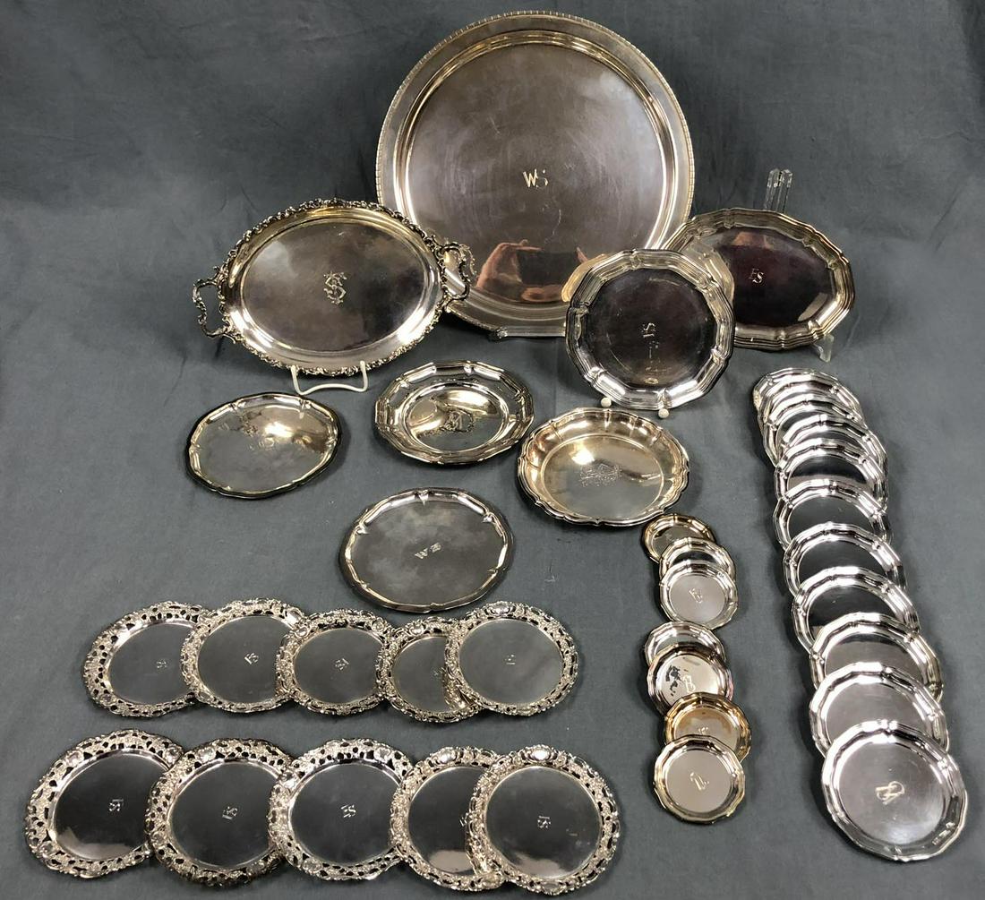 Silver. Plates and coasters with monograms. Mostly: Up to 32 cm in diameter. 2406 grams. German Description: Silber. Platten und Untersetzer mit Monogrammen. Meist Silber 800. Bis 32 cm Durchmesser. 2406 Gramm.