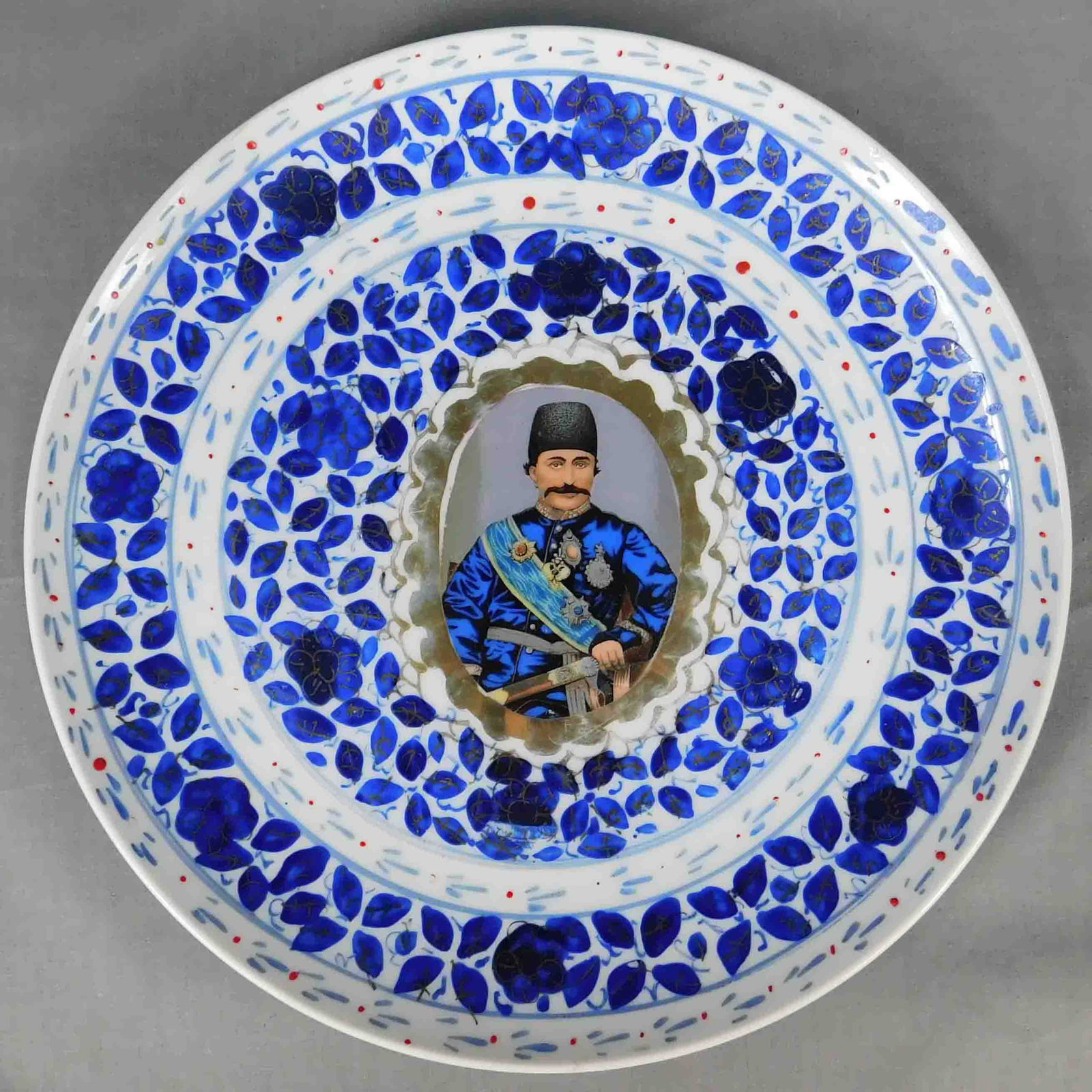 Porzellan Platte. Wohl Russland oder China.: 26 cm Durchmesser. Höchstwahrscheinlich aus der Zeit von 1848 bis 1893 für den Markt: Persien / Iran. Das Portrait des N?ser ad-Din Schah als Druck. Indigo und Gold hauptsächlich handge